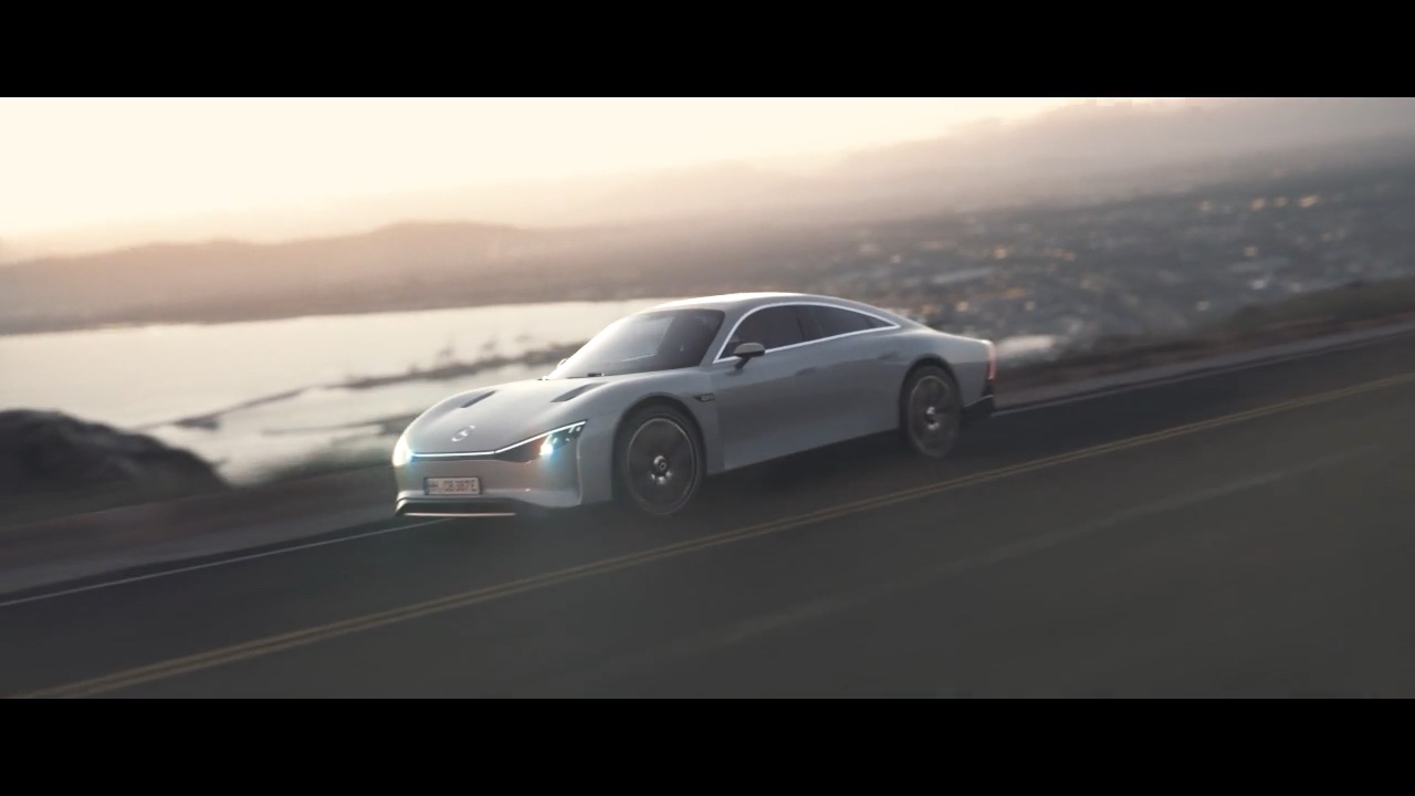 Silver Mercedes-Benz VISION EQXX driving on a mountain road, with the coast and a wide landscape in the background